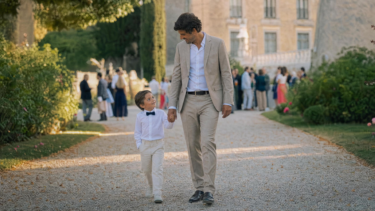 Enfant habillé pour un mariage marchant avec un adulte, tenue élégante et confortable. Obraz